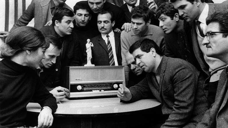 Griechische Gastarbeiter verfolgen am Radio die neuesten Nachrichten aus ihrem Heimatland.