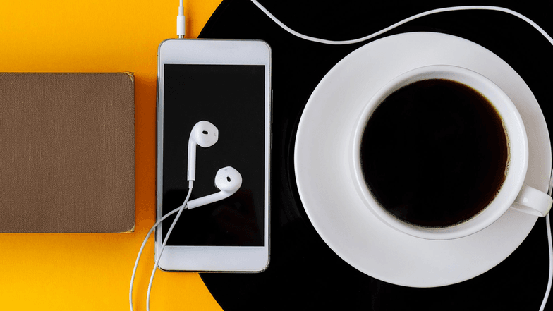Mobiltelefon mit Kopfhörern und eine Tasse schwarzer Kaffee auf Vinyl-Platte