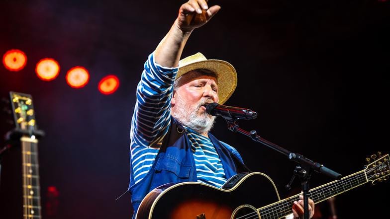 Schauspieler und Musiker Axel Prahl steht mit seiner Gitarre bei einem Konzertauftritt auf der Bühne.