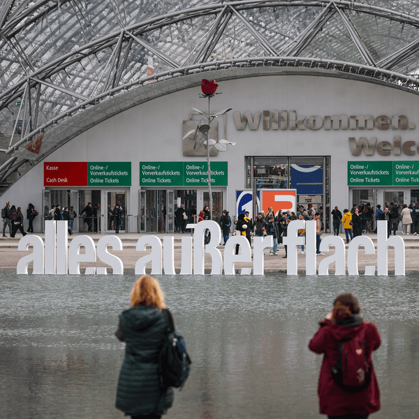 Besucher fotografieren den Schriftzug „alles außer flach“ vor der Leipziger Buchmesse.