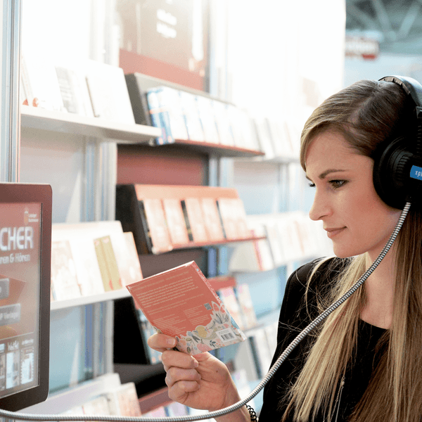 Eine junge Frau mit Kopfhörern beim Hören eines Hörbuches.