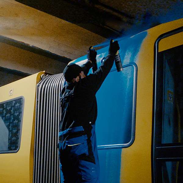 Graffitykünstler sprayen einen Zug in einem U-Bahn Schacht