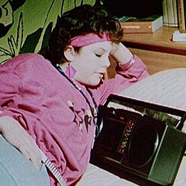 Frau mit Sitrnband liegt mit einem alten Radio auf dem Bett