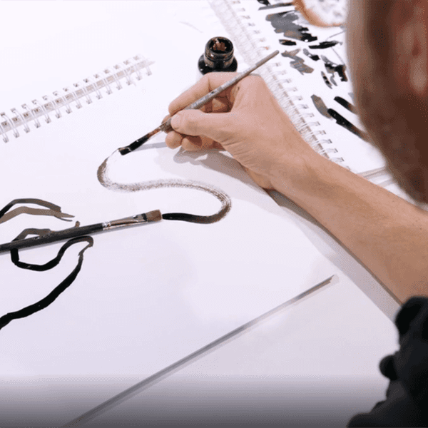 Ein Zeichner arbeitet mit einer Tuschefeder an einer Illustration.