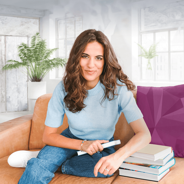 Eine Frau sitzt mit Büchern auf einer Couch
