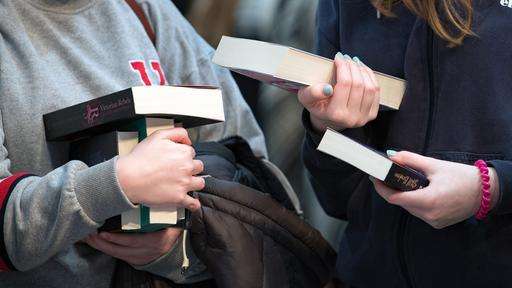 Besucherinnen der Leipziger Buchmesse betrachten Bücher an einem Verlagsstand