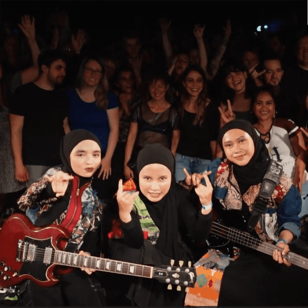 Drei Frauen mit E-Gitarren und in Hijab gekleidet auf einer Bühne.