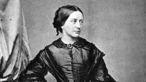 Schwarz-weiß Fotografie von Clara Schumann mit dunklen zusammengesteckten Haaren und einem dunklen Rüschenkleid.