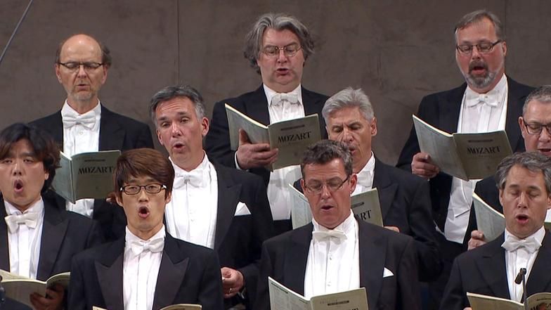 Männer singen und halten Hefte mit der Aufschrift Mozart in den Händen.
