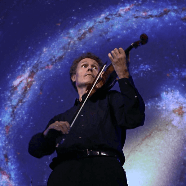 Ein Mann mit Violine steht vor einem Sternenhimmel und spielt auf seinem Instrument.